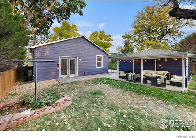 rear view of property featuring a patio area, an outdoor hangout area, a lawn, and fence