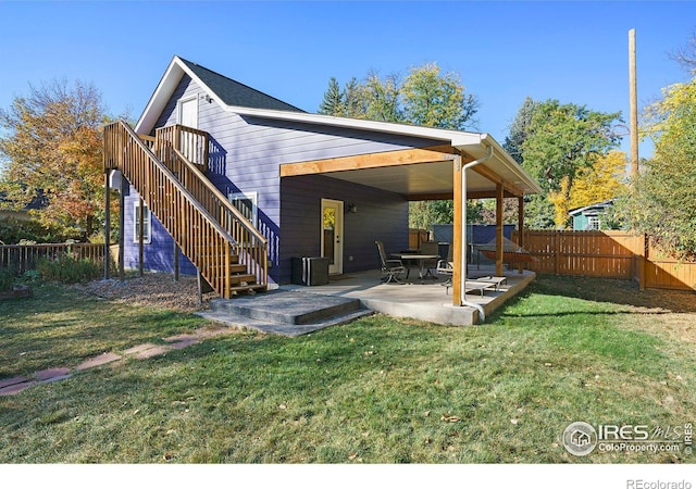 back of property with a yard, a patio, a fenced backyard, and stairs