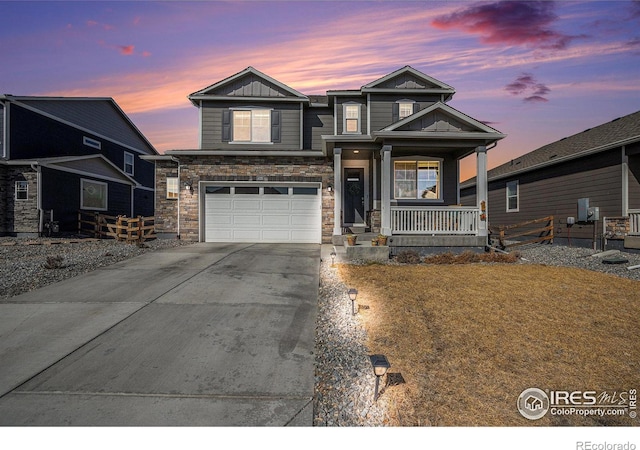 view of front of home featuring driveway, a porch, an attached garage, stone siding, and board and batten siding