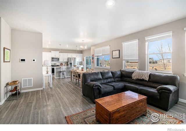 living room featuring visible vents, a healthy amount of sunlight, baseboards, and wood finished floors