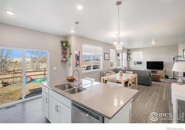 kitchen with visible vents, an island with sink, a sink, light wood-style floors, and dishwasher