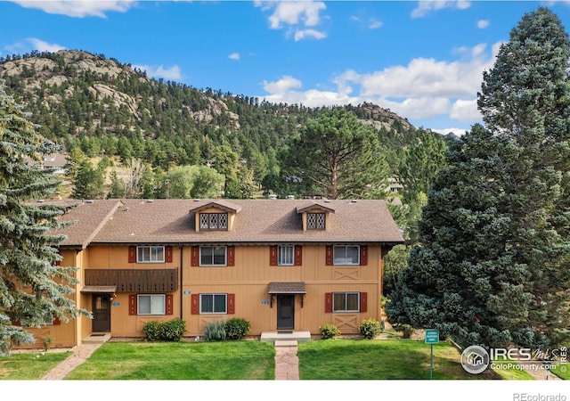 multi unit property featuring a mountain view, a front yard, and a shingled roof