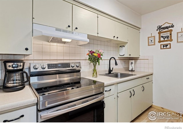 kitchen featuring under cabinet range hood, stainless steel electric range oven, light countertops, and a sink