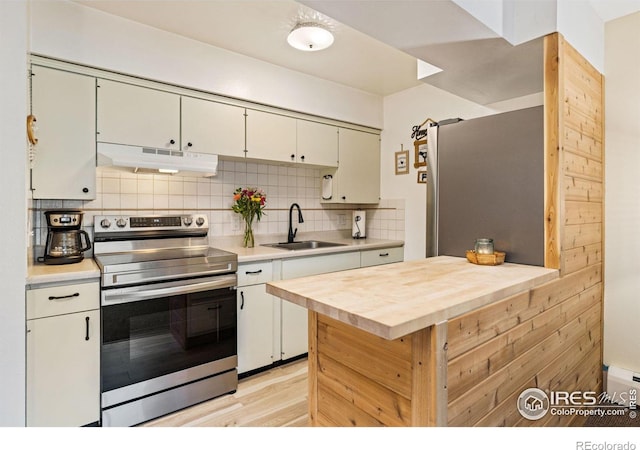 kitchen with light wood-style flooring, a sink, appliances with stainless steel finishes, under cabinet range hood, and backsplash