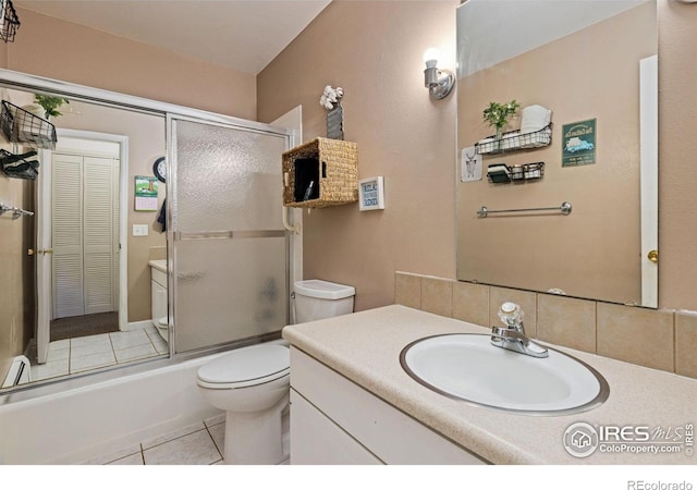 bathroom featuring tile patterned floors, toilet, backsplash, combined bath / shower with glass door, and vanity