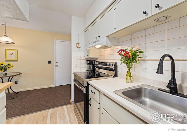 kitchen featuring stainless steel electric range oven, a sink, light countertops, under cabinet range hood, and tasteful backsplash