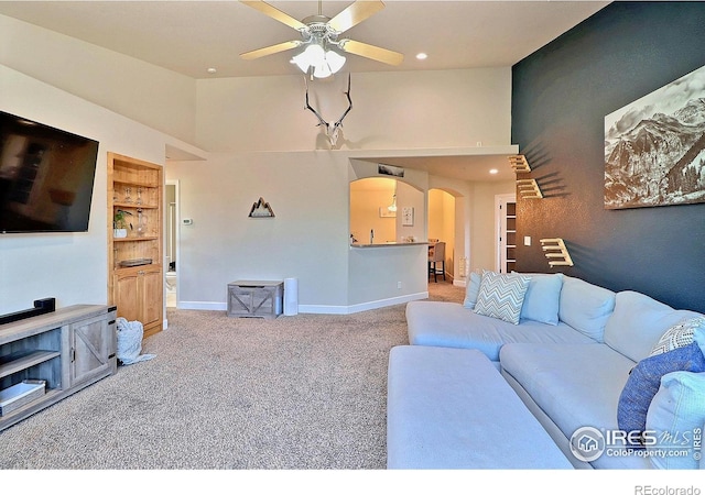 living room featuring baseboards, carpet, arched walkways, high vaulted ceiling, and a ceiling fan