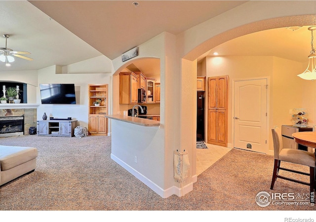 interior space featuring ceiling fan, light colored carpet, arched walkways, and a tile fireplace