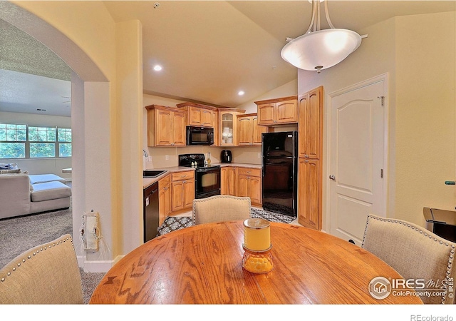 kitchen with black appliances, a sink, arched walkways, glass insert cabinets, and vaulted ceiling