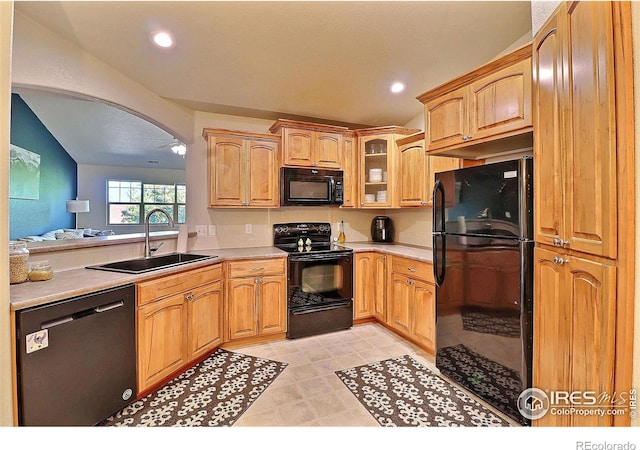 kitchen with arched walkways, black appliances, light countertops, and a sink