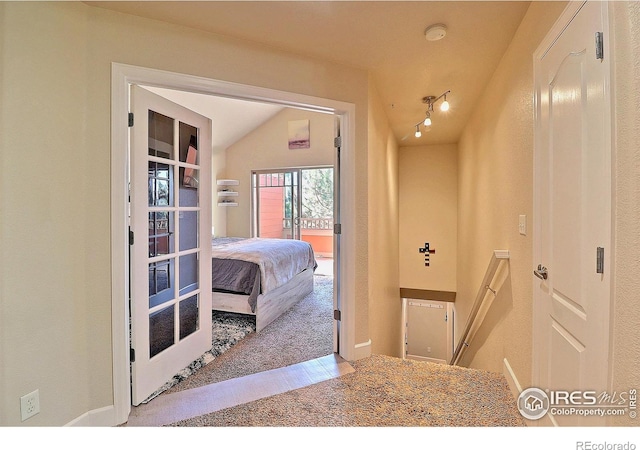 carpeted bedroom with vaulted ceiling and rail lighting