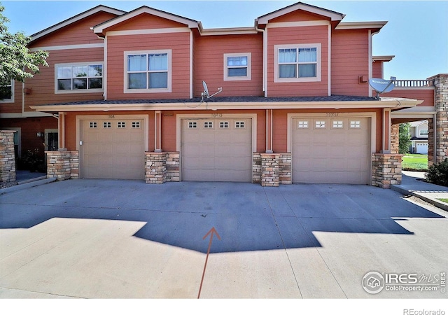 view of property featuring stone siding, driveway, and a garage