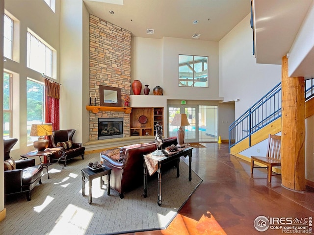 living room featuring a stone fireplace, stairs, visible vents, and finished concrete floors