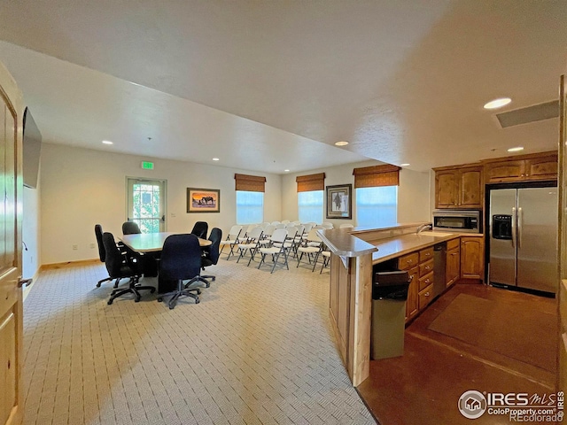 kitchen featuring light countertops, recessed lighting, brown cabinets, appliances with stainless steel finishes, and a peninsula