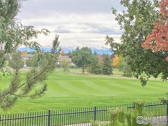 view of property's community with a yard, view of golf course, and fence