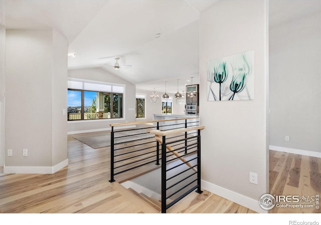 interior space featuring wood finished floors, baseboards, and vaulted ceiling