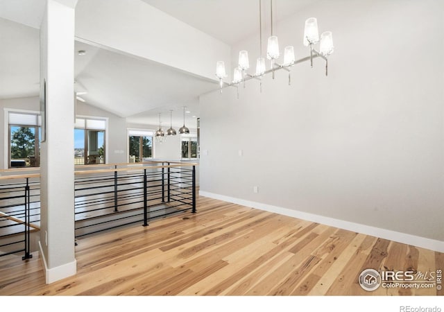 dining room featuring vaulted ceiling, wood finished floors, baseboards, and a chandelier