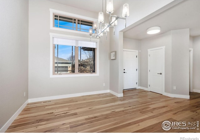 foyer featuring an inviting chandelier, baseboards, and wood finished floors