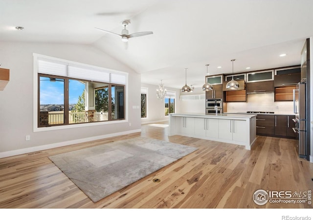 kitchen featuring backsplash, light wood-style floors, light countertops, lofted ceiling, and stainless steel gas cooktop