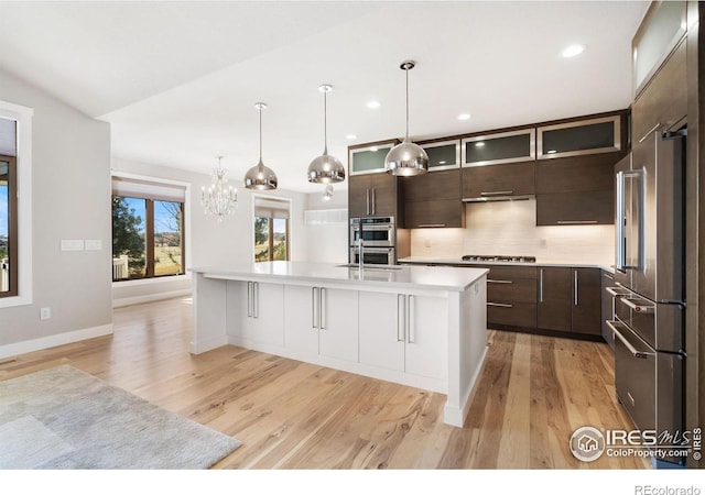 kitchen with tasteful backsplash, stainless steel appliances, light countertops, glass insert cabinets, and dark brown cabinets