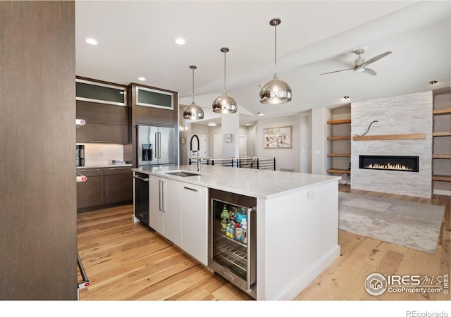 kitchen featuring beverage cooler, high quality fridge, light wood-type flooring, and a sink