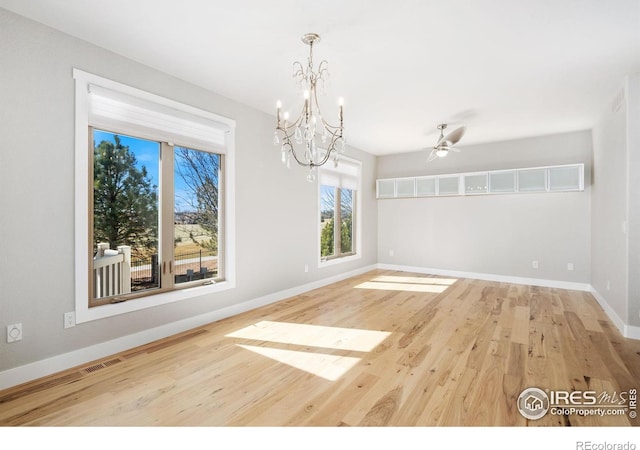 unfurnished dining area featuring visible vents, baseboards, an inviting chandelier, and wood finished floors