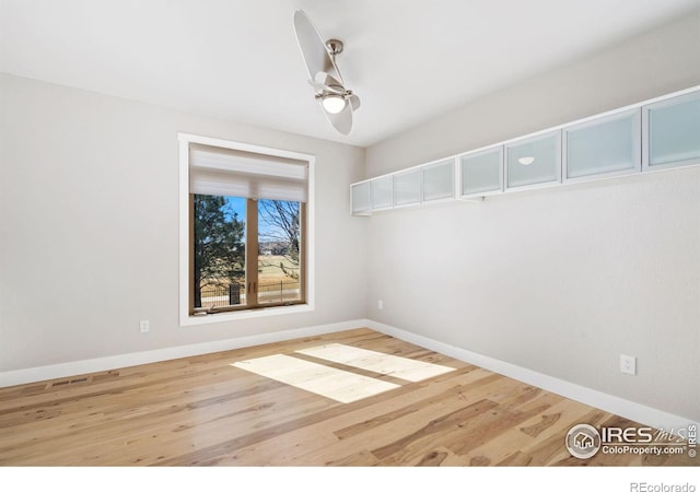 empty room with wood finished floors, baseboards, and ceiling fan