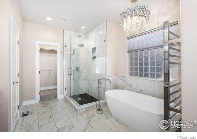 full bath featuring a walk in closet, a shower stall, a freestanding tub, and marble finish floor