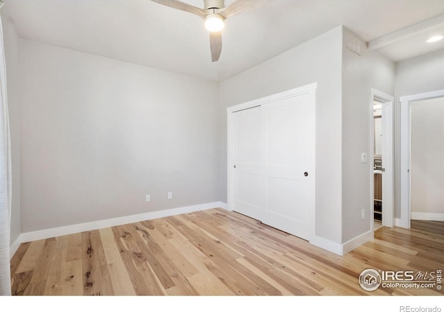 unfurnished bedroom featuring a closet, a ceiling fan, baseboards, and light wood finished floors