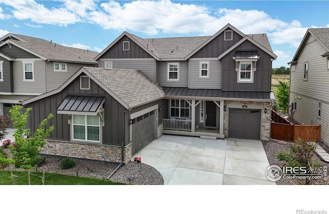 view of front of home with stone siding, board and batten siding, concrete driveway, and a standing seam roof