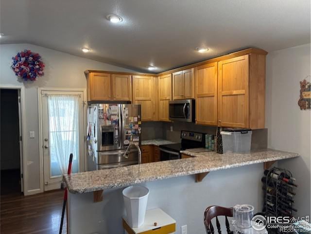 kitchen featuring stainless steel appliances, a peninsula, a breakfast bar area, light stone countertops, and vaulted ceiling