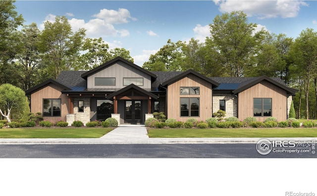 view of front of home featuring a front lawn, french doors, and stone siding