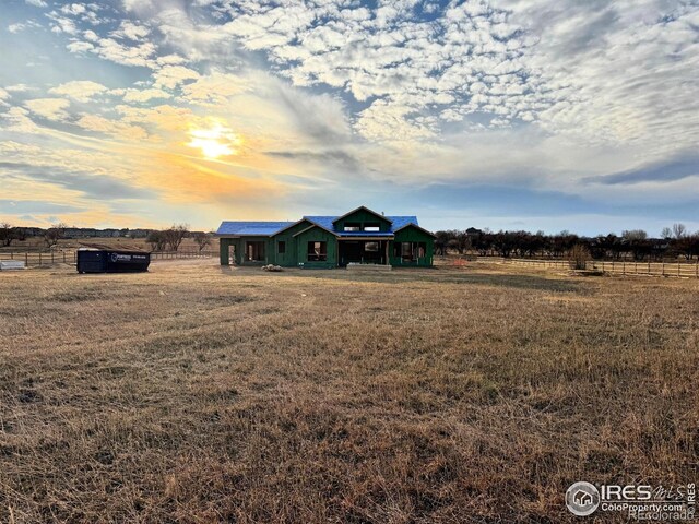 view of front of property featuring a rural view, a front lawn, and fence