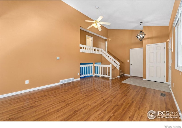 foyer entrance with visible vents, high vaulted ceiling, wood finished floors, stairway, and baseboards