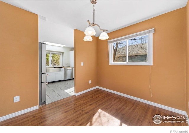 unfurnished dining area featuring a barn door, light wood-style floors, and baseboards