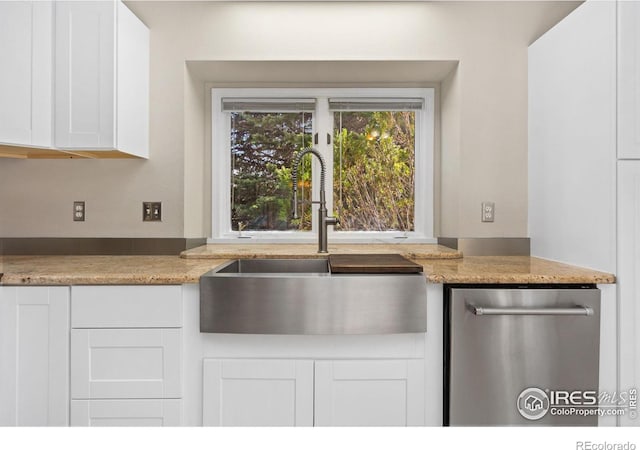 kitchen featuring a sink, light stone countertops, stainless steel dishwasher, and white cabinetry