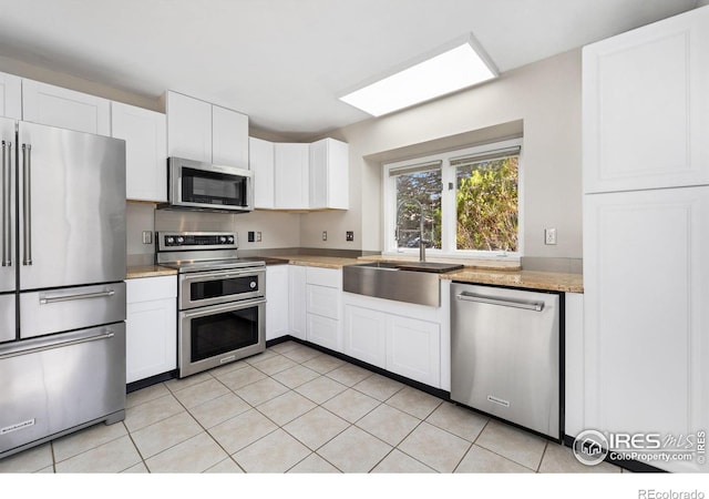 kitchen with light tile patterned floors, white cabinetry, stainless steel appliances, and a sink