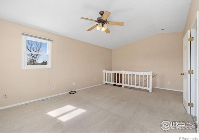 spare room with carpet floors, visible vents, baseboards, and vaulted ceiling