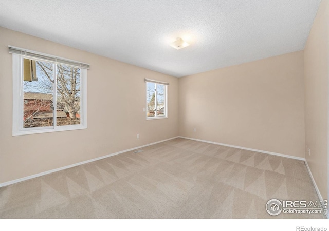 carpeted empty room featuring baseboards and a textured ceiling