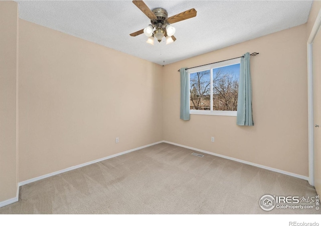 carpeted spare room featuring visible vents, baseboards, and a textured ceiling