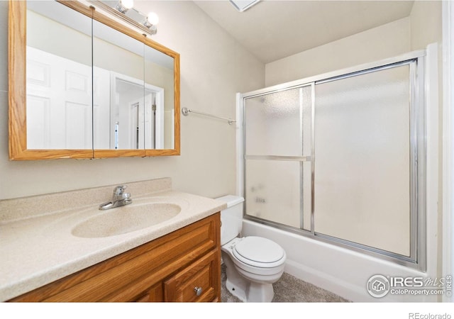 full bath with vanity, toilet, and bath / shower combo with glass door