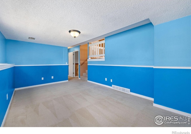 carpeted spare room with visible vents, stairway, and baseboards