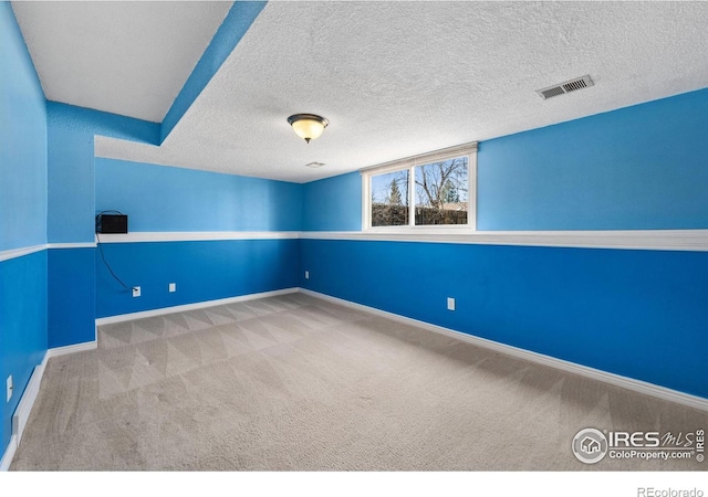 empty room with visible vents, carpet flooring, a textured ceiling, and baseboards