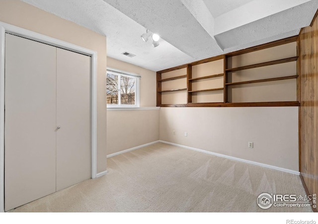 unfurnished bedroom with visible vents, baseboards, carpet floors, a closet, and a textured ceiling