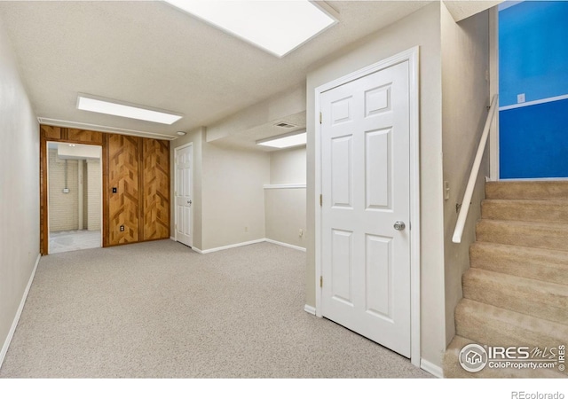 finished basement with stairway, baseboards, and carpet floors