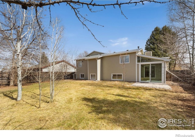 rear view of house featuring a yard and fence