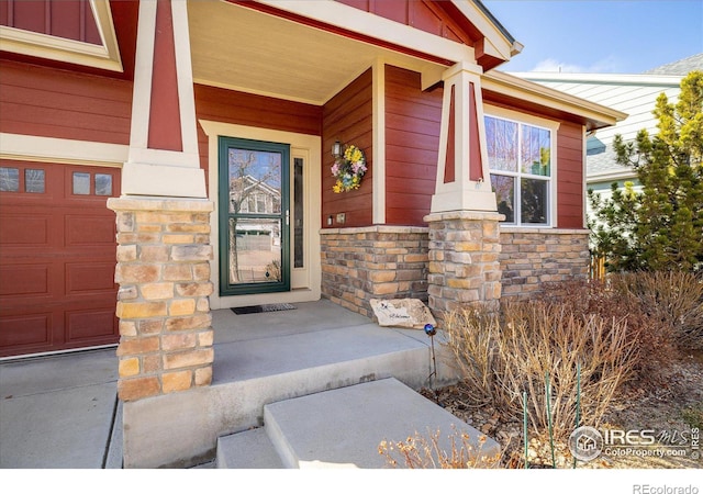 view of exterior entry with stone siding, covered porch, and board and batten siding