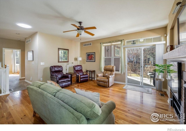 living room with visible vents, baseboards, wood finished floors, and a fireplace