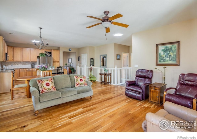 living room with light wood-style flooring and ceiling fan with notable chandelier