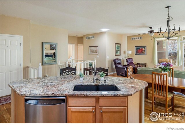 kitchen featuring wood finished floors, visible vents, a sink, stainless steel dishwasher, and open floor plan